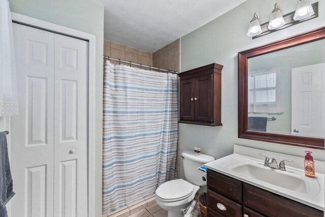 bathroom with vanity, tile patterned floors, toilet, a textured ceiling, and walk in shower