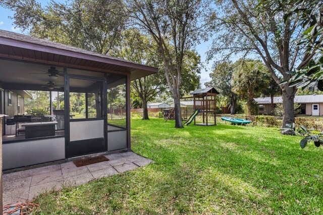 view of yard with a playground, a sunroom, and ceiling fan