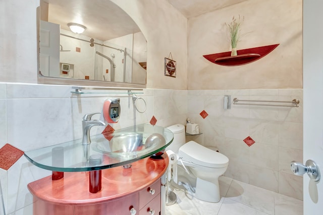 bathroom featuring toilet, tile patterned flooring, vanity, tile walls, and walk in shower