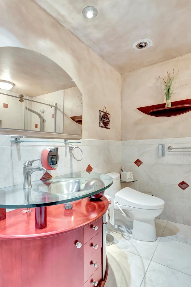 bathroom with vanity, toilet, tile walls, and tile patterned flooring