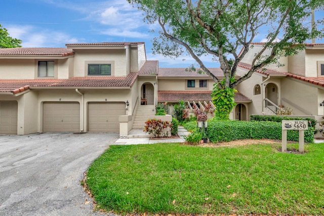 mediterranean / spanish-style home featuring a front lawn and a garage