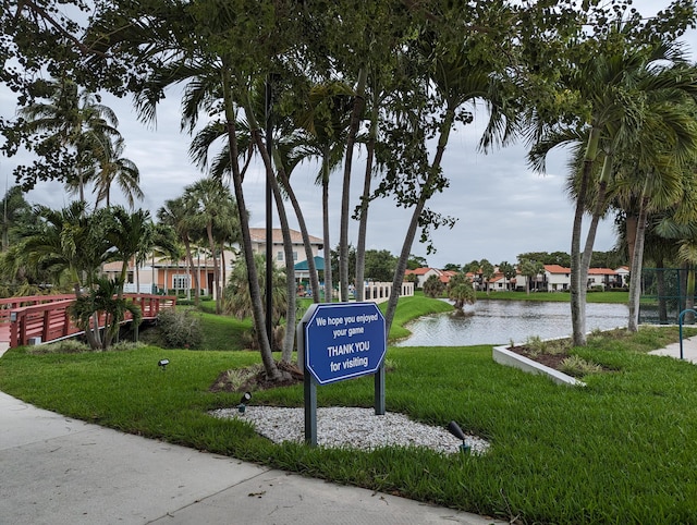 surrounding community with a water view and a lawn