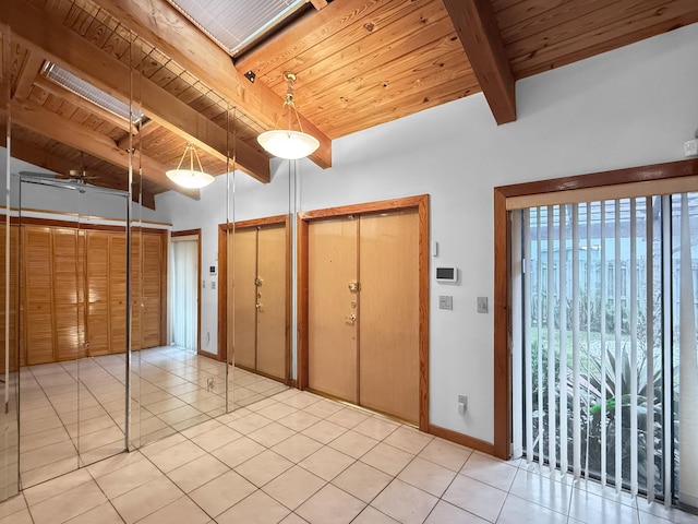 unfurnished bedroom with two closets, beamed ceiling, wood ceiling, and light tile patterned floors