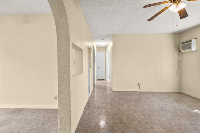 spare room with a wall unit AC, a textured ceiling, and ceiling fan