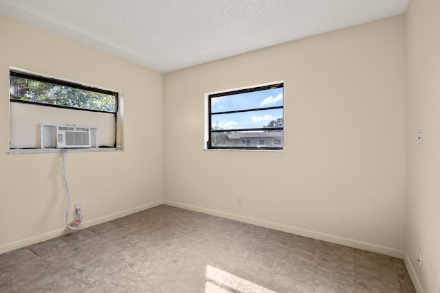 empty room featuring a textured ceiling, cooling unit, and a healthy amount of sunlight