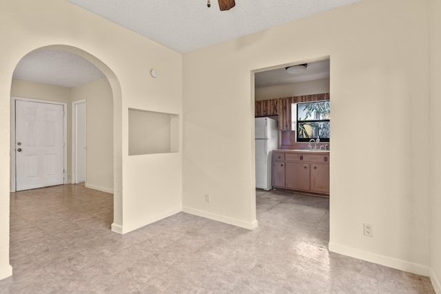 empty room featuring sink, a textured ceiling, and ceiling fan