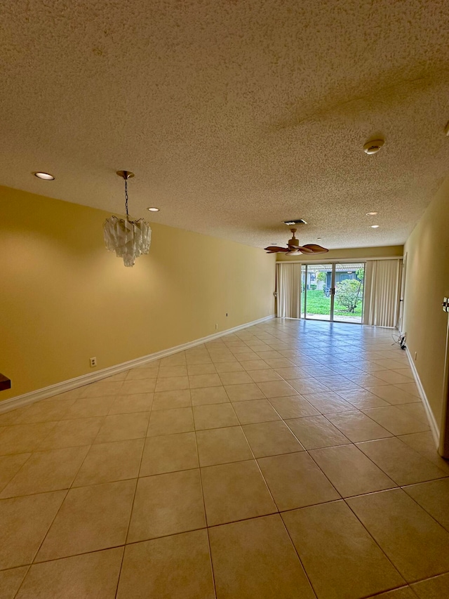 tiled spare room featuring a textured ceiling and ceiling fan with notable chandelier