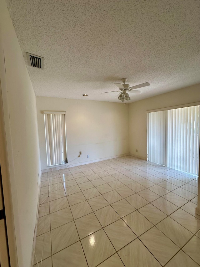 tiled empty room with a textured ceiling and ceiling fan