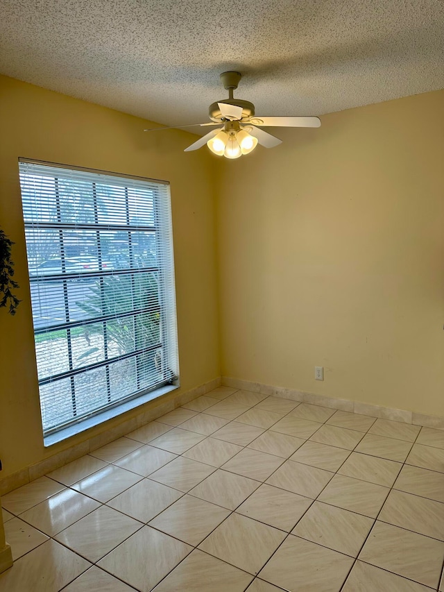 tiled spare room with ceiling fan, a textured ceiling, and a wealth of natural light