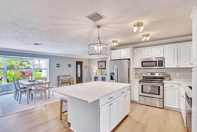 kitchen with a kitchen island, stainless steel appliances, pendant lighting, light wood-type flooring, and white cabinets