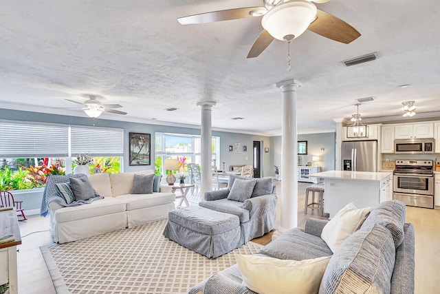 living room with a textured ceiling, decorative columns, ceiling fan, light hardwood / wood-style floors, and ornamental molding