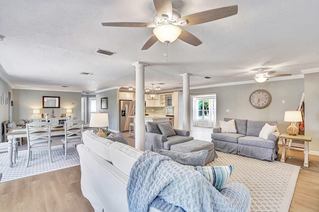 living room featuring light hardwood / wood-style floors, crown molding, ceiling fan, and decorative columns