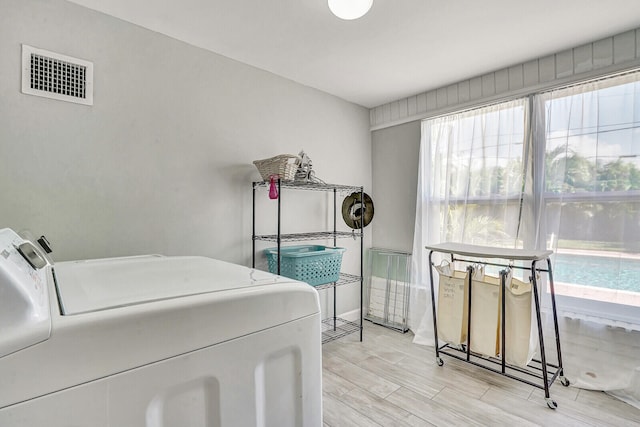 laundry area with light hardwood / wood-style flooring and washing machine and clothes dryer