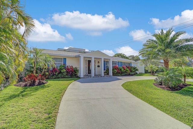704 Eastwind Dr, North Palm Beach, FL 33408 - view of front facade featuring stucco siding, roof mounted solar panels, a front lawn, and curved driveway