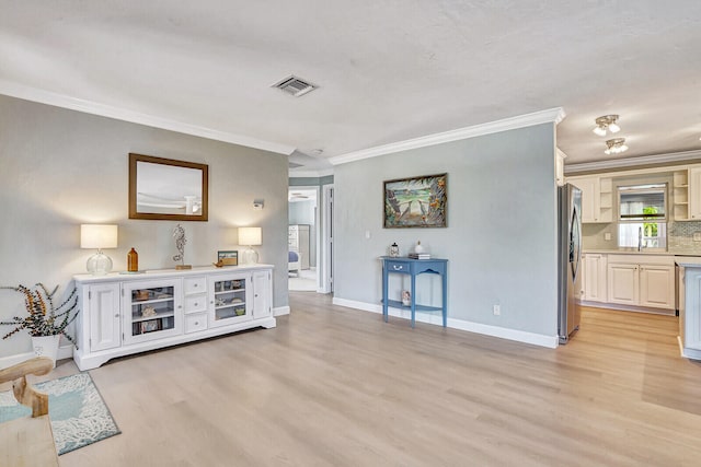 living room with light hardwood / wood-style floors, ornamental molding, and sink