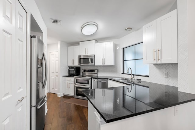 kitchen featuring appliances with stainless steel finishes, dark hardwood / wood-style flooring, kitchen peninsula, and white cabinets