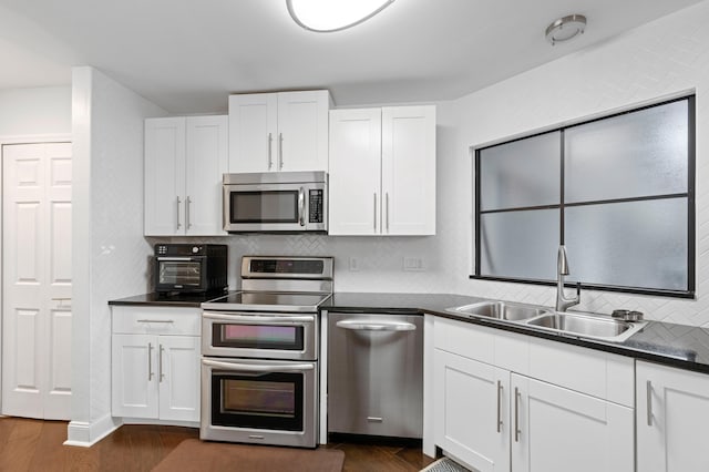 kitchen featuring appliances with stainless steel finishes, white cabinets, sink, and dark hardwood / wood-style floors