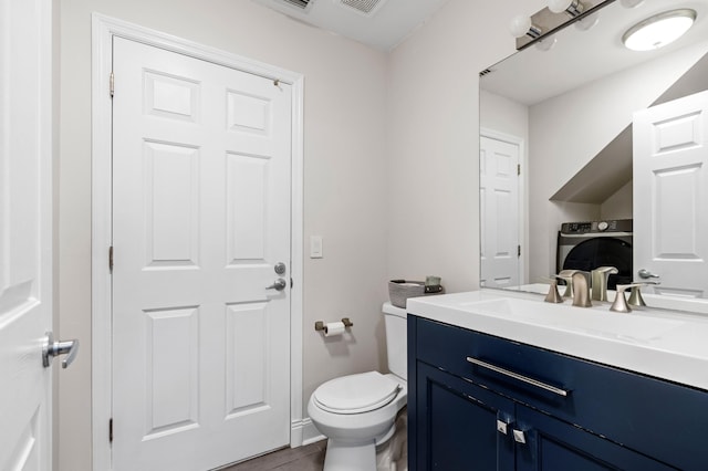 bathroom featuring toilet, vanity, and washer / dryer