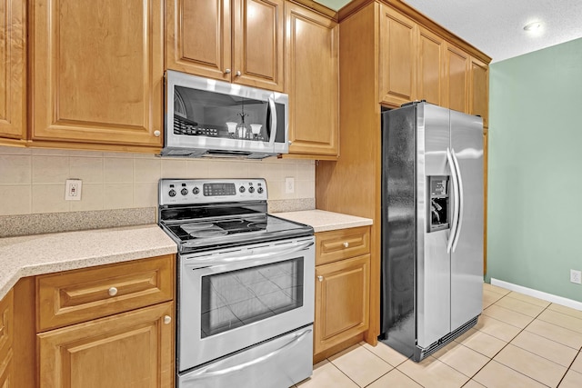 kitchen with a textured ceiling, decorative backsplash, stainless steel appliances, and light tile patterned floors