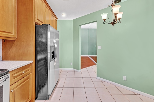 kitchen featuring light stone countertops, a notable chandelier, pendant lighting, light tile patterned flooring, and appliances with stainless steel finishes