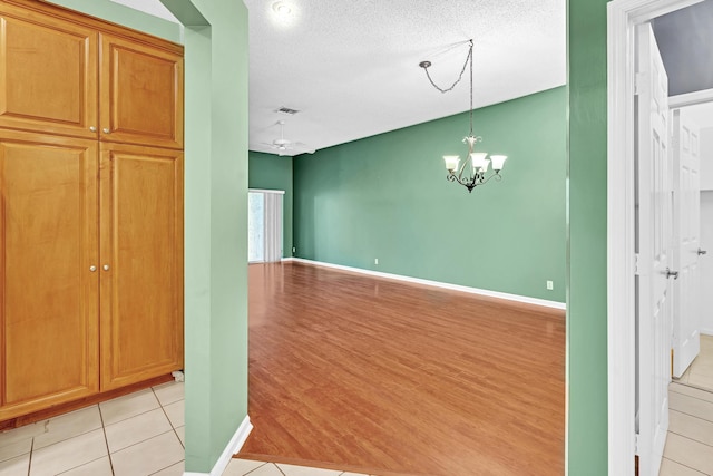 interior space with pendant lighting, a textured ceiling, a chandelier, and light wood-type flooring