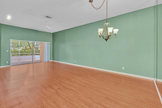 spare room with wood-type flooring and ceiling fan with notable chandelier