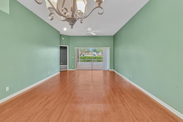 spare room featuring light wood-type flooring and ceiling fan with notable chandelier