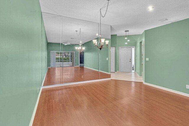 interior space with a textured ceiling, light hardwood / wood-style flooring, and an inviting chandelier