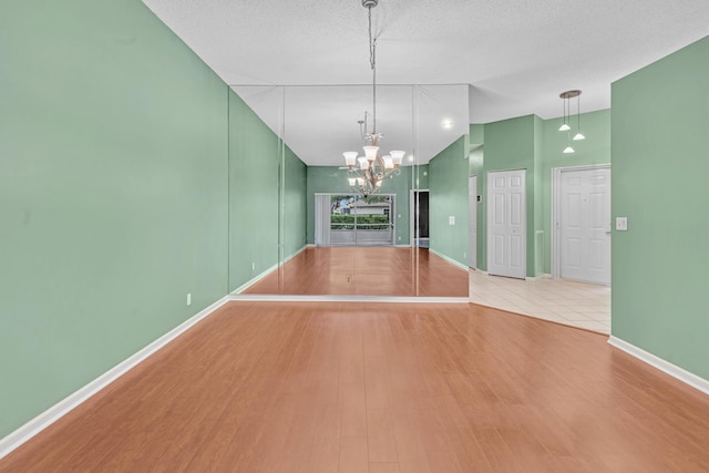 unfurnished room with high vaulted ceiling, a textured ceiling, and light hardwood / wood-style flooring