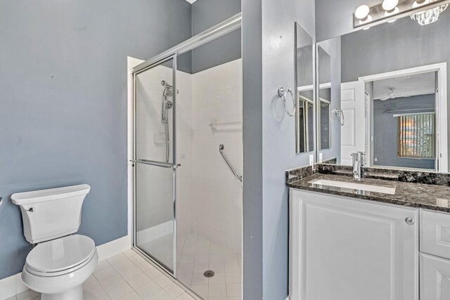 bathroom featuring vanity, tile patterned flooring, toilet, and a shower with door