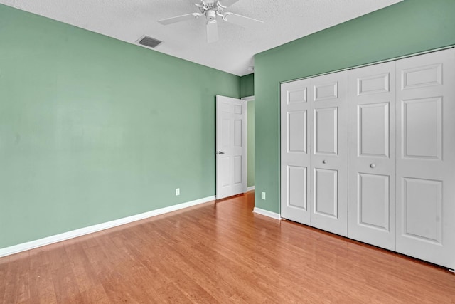 unfurnished bedroom featuring a closet, ceiling fan, a textured ceiling, and light hardwood / wood-style floors