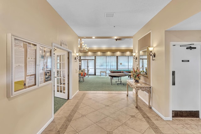 corridor featuring a notable chandelier and light colored carpet