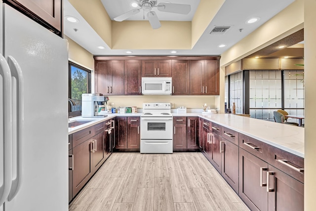 kitchen with kitchen peninsula, sink, light stone countertops, light wood-type flooring, and white appliances