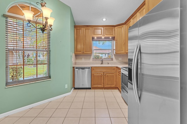 kitchen featuring stainless steel appliances, sink, light tile patterned floors, a chandelier, and a textured ceiling