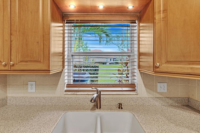 kitchen featuring sink, light stone counters, and backsplash