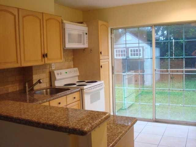 kitchen with light brown cabinets, sink, light stone counters, and white appliances