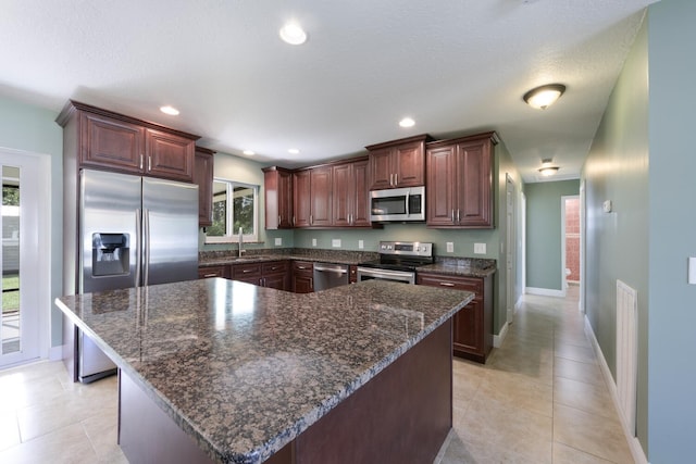 kitchen featuring sink, light tile patterned floors, a center island, and stainless steel appliances