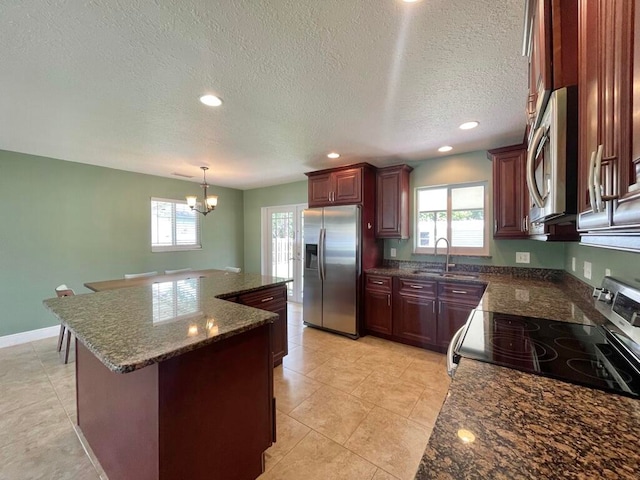 kitchen featuring appliances with stainless steel finishes, a center island, decorative light fixtures, sink, and a chandelier