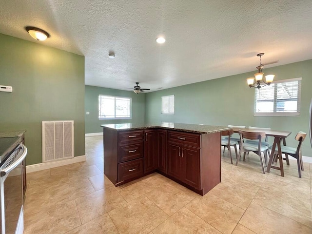 kitchen featuring decorative light fixtures, dark stone countertops, stainless steel range with electric cooktop, a textured ceiling, and ceiling fan with notable chandelier