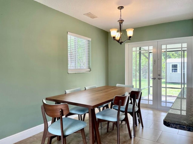 dining space featuring light tile patterned flooring, french doors, and a notable chandelier