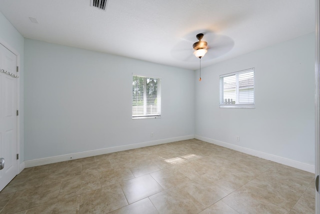 spare room with ceiling fan, a wealth of natural light, and light tile patterned flooring