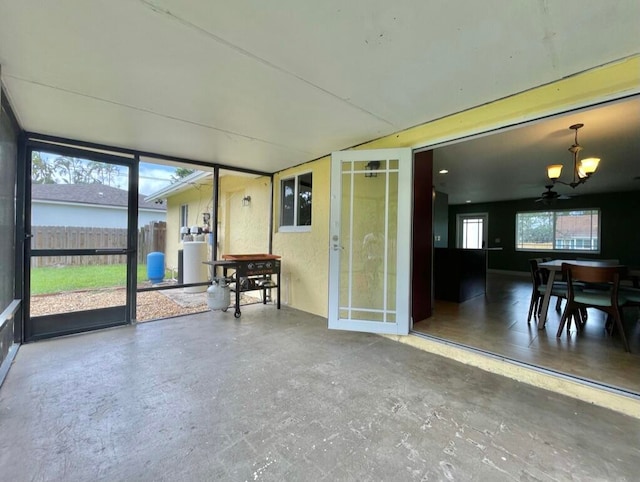 interior space with concrete flooring and ceiling fan with notable chandelier