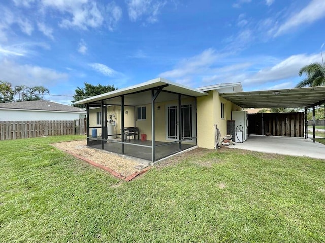 back of property featuring a lawn, a carport, and a sunroom