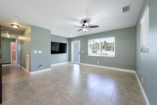 tiled empty room featuring ceiling fan