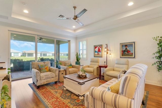 living room featuring hardwood / wood-style floors, a tray ceiling, and ceiling fan