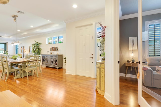 dining space with crown molding, a raised ceiling, and hardwood / wood-style floors