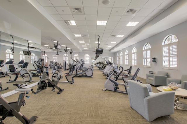 gym with a paneled ceiling and light carpet