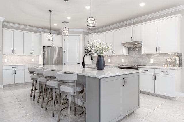 kitchen featuring white cabinets, a kitchen island with sink, stainless steel appliances, and decorative light fixtures