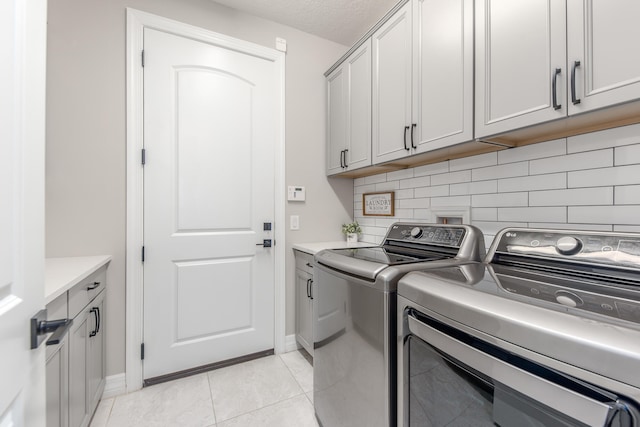 washroom with cabinets, light tile patterned flooring, and washing machine and clothes dryer