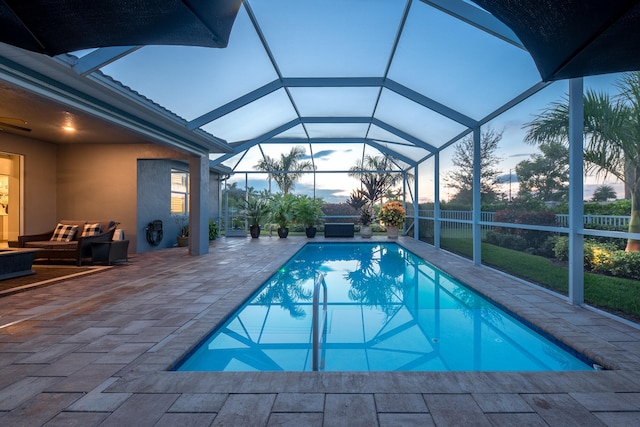 pool at dusk featuring a patio area and a lanai